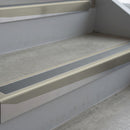 Mirroflect Silver deep-riser square-edge aluminium stair nosing fitted along two bare concrete steps, 62mm tread plate and 56mm front face, with a Mid Grey anti-slip insert running the full width of each step