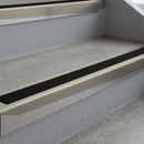 Mirroflect Silver deep-riser square-edge aluminium stair nosing fitted along two bare concrete steps, 62mm tread plate and 56mm front face, with a Premium Black anti-slip insert running the full width of each step