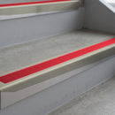 Mirroflect Silver deep-riser square-edge aluminium stair nosing fitted along two bare concrete steps, 62mm tread plate and 56mm front face, with a Red anti-slip insert running the full width of each step