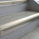 Mirroflect Silver deep-riser square-edge aluminium stair nosing fitted along two bare concrete steps, 62mm tread plate and 56mm front face, with a White anti-slip insert running the full width of each step