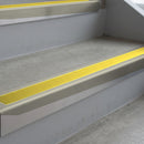 Mirroflect Silver deep-riser square-edge aluminium stair nosing fitted along two bare concrete steps, 62mm tread plate and 56mm front face, with a Yellow anti-slip insert running the full width of each step