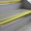Mirrorflect Gold deep-riser square-edge aluminium stair nosing fitted along two bare concrete steps, 62mm tread plate and 56mm front face, with a Apple Green anti-slip insert running the full width of each step