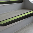 Satin Black deep-riser square-edge aluminium stair nosing fitted along two bare concrete steps, 62mm tread plate and 56mm front face, with a Apple Green anti-slip insert running the full width of each step