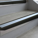 Satin Black deep-riser square-edge aluminium stair nosing fitted along two bare concrete steps, 62mm tread plate and 56mm front face, with a Aura anti-slip insert running the full width of each step