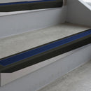 Satin Black deep-riser square-edge aluminium stair nosing fitted along two bare concrete steps, 62mm tread plate and 56mm front face, with a Dark Blue anti-slip insert running the full width of each step