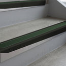 Satin Black deep-riser square-edge aluminium stair nosing fitted along two bare concrete steps, 62mm tread plate and 56mm front face, with a Dark Green anti-slip insert running the full width of each step