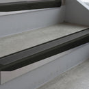 Satin Black deep-riser square-edge aluminium stair nosing fitted along two bare concrete steps, 62mm tread plate and 56mm front face, with a Dark Grey anti-slip insert running the full width of each step