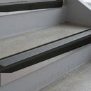 Satin Black deep-riser square-edge aluminium stair nosing fitted along two bare concrete steps, 62mm tread plate and 56mm front face, with a Mid Grey anti-slip insert running the full width of each step