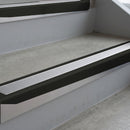Satin Black deep-riser square-edge aluminium stair nosing fitted along two bare concrete steps, 62mm tread plate and 56mm front face, with a Polar Grey anti-slip insert running the full width of each step