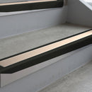 Satin Black deep-riser square-edge aluminium stair nosing fitted along two bare concrete steps, 62mm tread plate and 56mm front face, with a Sahara anti-slip insert running the full width of each step