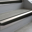 Satin Black deep-riser square-edge aluminium stair nosing fitted along two bare concrete steps, 62mm tread plate and 56mm front face, with a White anti-slip insert running the full width of each step