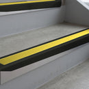 Satin Black deep-riser square-edge aluminium stair nosing fitted along two bare concrete steps, 62mm tread plate and 56mm front face, with a Yellow anti-slip insert running the full width of each step