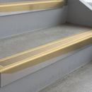Satin Bronze deep-riser square-edge aluminium stair nosing fitted along two bare concrete steps, 62mm tread plate and 56mm front face, with a Beige anti-slip insert running the full width of each step