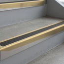 Satin Bronze deep-riser square-edge aluminium stair nosing fitted along two bare concrete steps, 62mm tread plate and 56mm front face, with a Dark Grey anti-slip insert running the full width of each step