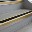Satin Bronze deep-riser square-edge aluminium stair nosing fitted along two bare concrete steps, 62mm tread plate and 56mm front face, with a Premium Black anti-slip insert running the full width of each step