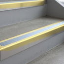 Satin Gold deep-riser square-edge aluminium stair nosing fitted along two bare concrete steps, 62mm tread plate and 56mm front face, with a Aura anti-slip insert running the full width of each step