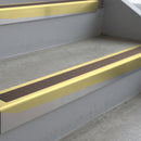 Satin Gold deep-riser square-edge aluminium stair nosing fitted along two bare concrete steps, 62mm tread plate and 56mm front face, with a Brown anti-slip insert running the full width of each step
