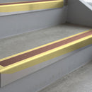 Satin Gold deep-riser square-edge aluminium stair nosing fitted along two bare concrete steps, 62mm tread plate and 56mm front face, with a Mid Brown anti-slip insert running the full width of each step