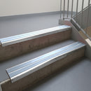 Mill Finish aluminium stair nosing fitted along two concrete steps in an office stairwell, with twin Aura anti-slip inserts running the full width of each step