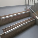 Mill Finish aluminium stair nosing fitted along two concrete steps in an office stairwell, with twin Brown anti-slip inserts running the full width of each step