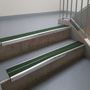 Mill Finish aluminium stair nosing fitted along two concrete steps in an office stairwell, with twin Dark Green anti-slip inserts running the full width of each step