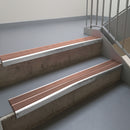 Mill Finish aluminium stair nosing fitted along two concrete steps in an office stairwell, with twin Mid Brown anti-slip inserts running the full width of each step
