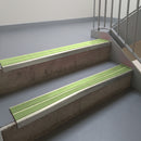 Mirroflect Silver aluminium stair nosing fitted along two concrete steps in an office stairwell, with twin Apple Green anti-slip inserts running the full width of each step