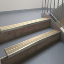 Mirroflect Silver aluminium stair nosing fitted along two concrete steps in an office stairwell, with twin Beige anti-slip inserts running the full width of each step