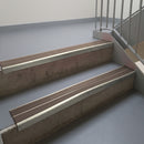 Mirroflect Silver aluminium stair nosing fitted along two concrete steps in an office stairwell, with twin Brown anti-slip inserts running the full width of each step