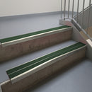 Mirroflect Silver aluminium stair nosing fitted along two concrete steps in an office stairwell, with twin Dark Green anti-slip inserts running the full width of each step