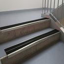 Mirroflect Silver aluminium stair nosing fitted along two concrete steps in an office stairwell, with twin Premium Black anti-slip inserts running the full width of each step