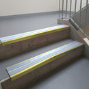 Mirrorflect Gold aluminium stair nosing fitted along two concrete steps in an office stairwell, with twin Aura anti-slip inserts running the full width of each step