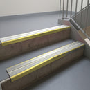 Mirrorflect Gold aluminium stair nosing fitted along two concrete steps in an office stairwell, with twin Oyster anti-slip inserts running the full width of each step