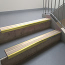 Mirrorflect Gold aluminium stair nosing fitted along two concrete steps in an office stairwell, with twin Sahara anti-slip inserts running the full width of each step