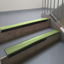Satin Black aluminium stair nosing fitted along two concrete steps in an office stairwell, with twin Apple Green anti-slip inserts running the full width of each step