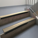 Satin Black aluminium stair nosing fitted along two concrete steps in an office stairwell, with twin Beige anti-slip inserts running the full width of each step