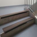Satin Black aluminium stair nosing fitted along two concrete steps in an office stairwell, with twin Brown anti-slip inserts running the full width of each step