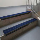 Satin Black aluminium stair nosing fitted along two concrete steps in an office stairwell, with twin Dark Blue anti-slip inserts running the full width of each step