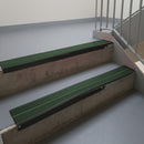 Satin Black aluminium stair nosing fitted along two concrete steps in an office stairwell, with twin Dark Green anti-slip inserts running the full width of each step
