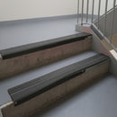 Satin Black aluminium stair nosing fitted along two concrete steps in an office stairwell, with twin Dark Grey anti-slip inserts running the full width of each step