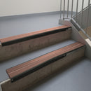 Satin Black aluminium stair nosing fitted along two concrete steps in an office stairwell, with twin Mid Brown anti-slip inserts running the full width of each step