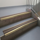 Satin Bronze aluminium stair nosing fitted along two concrete steps in an office stairwell, with twin Brown anti-slip inserts running the full width of each step