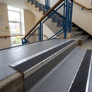 Mill finish aluminium stair nosing with coal insert fitted along concrete treads in a school stairwell