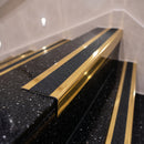 Mirrorflect gold aluminium stair nosing with coal insert on black terrazzo treads in a retail store staircase