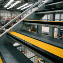 Satin black aluminium stair nosing with brimstone insert on steel mezzanine steps in a warehouse