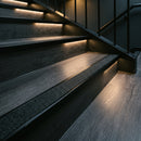 Satin black aluminium stair nosing with coal insert on dark timber treads in a low-lit office staircase