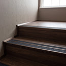 Dark bronze double channel stair nosings with twin coal anti-slip inserts on walnut effect hotel corridor stair treads