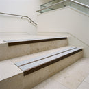 Dark bronze double channel stair nosings with twin everest anti-slip inserts on pale limestone museum stair treads