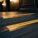 Mirrorflect gold double channel stair nosings with twin brimstone anti-slip inserts on a dark theatre foyer staircase