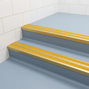 Satin gold double channel stair nosings with twin brimstone anti-slip inserts on blue-grey vinyl leisure centre stair treads